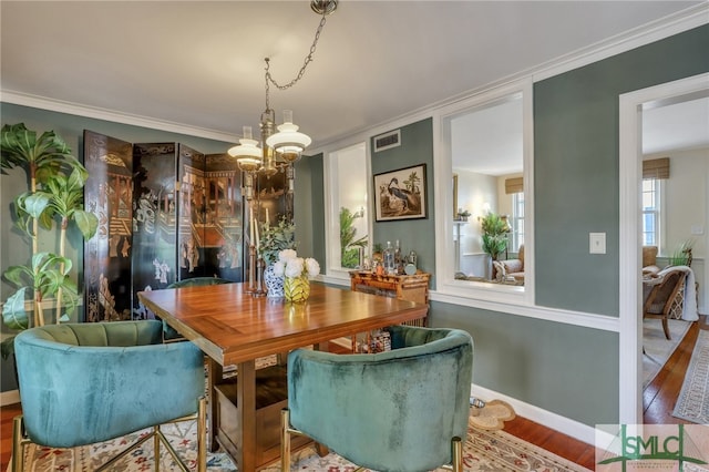 dining area with a chandelier, ornamental molding, and hardwood / wood-style flooring