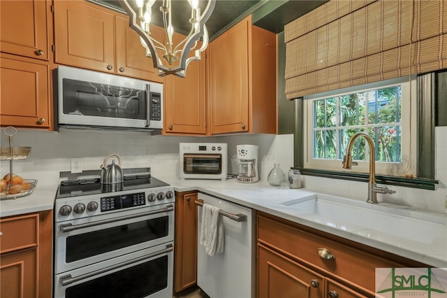 kitchen featuring light stone countertops, appliances with stainless steel finishes, sink, and a notable chandelier