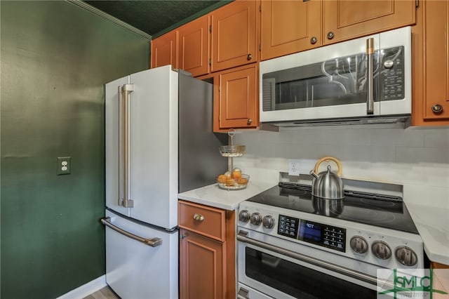 kitchen with backsplash, appliances with stainless steel finishes, light stone counters, and ornamental molding