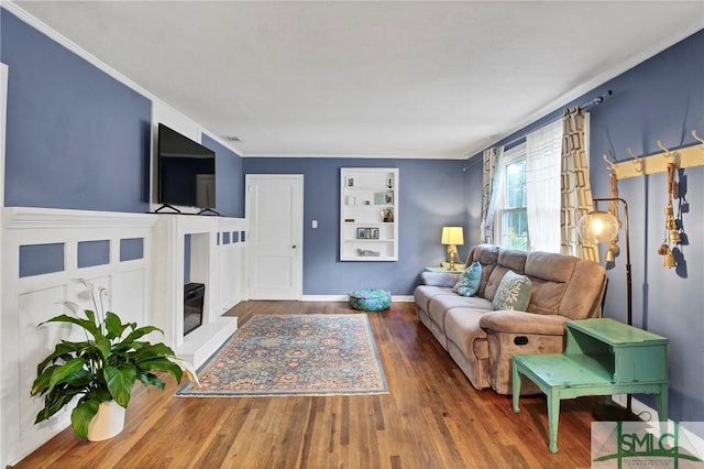 living room with built in shelves, ornamental molding, and hardwood / wood-style floors