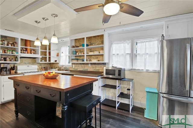 kitchen featuring appliances with stainless steel finishes, pendant lighting, a healthy amount of sunlight, and butcher block counters