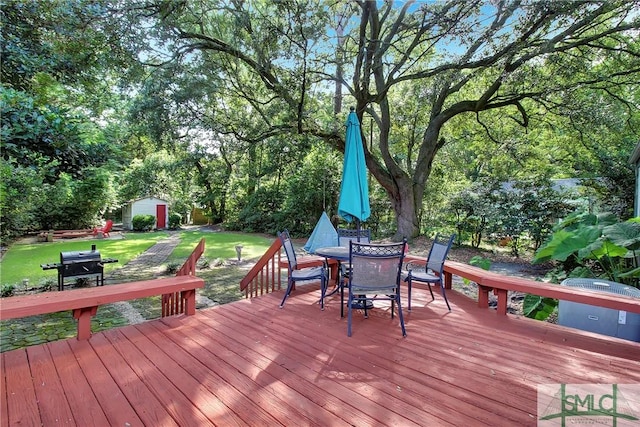 wooden deck featuring a yard, area for grilling, and a storage unit