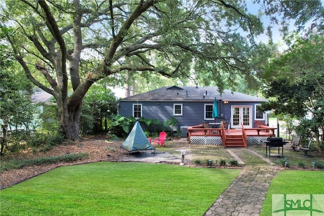 rear view of property featuring a lawn, french doors, and a wooden deck