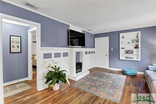 living room with built in shelves, ornamental molding, and hardwood / wood-style flooring