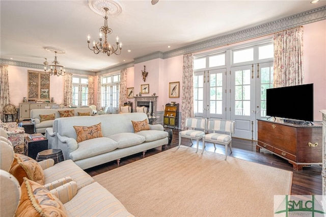 living room with ornamental molding, an inviting chandelier, and dark hardwood / wood-style floors