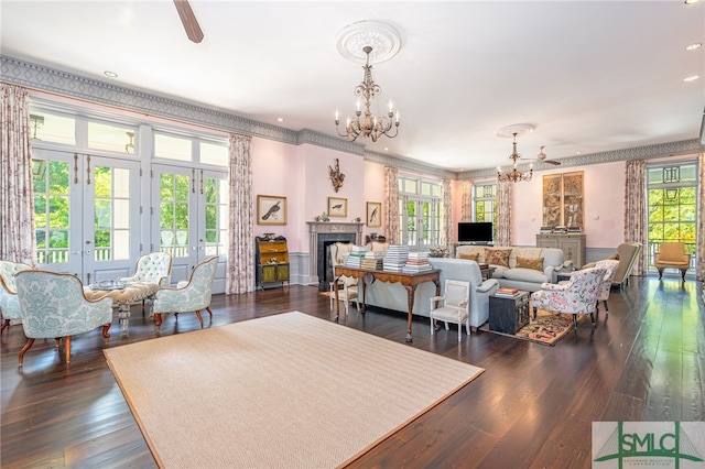 living room with ornamental molding, french doors, dark wood-type flooring, and ceiling fan with notable chandelier