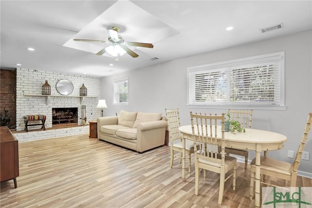 living room featuring ceiling fan, a brick fireplace, a healthy amount of sunlight, and light hardwood / wood-style flooring