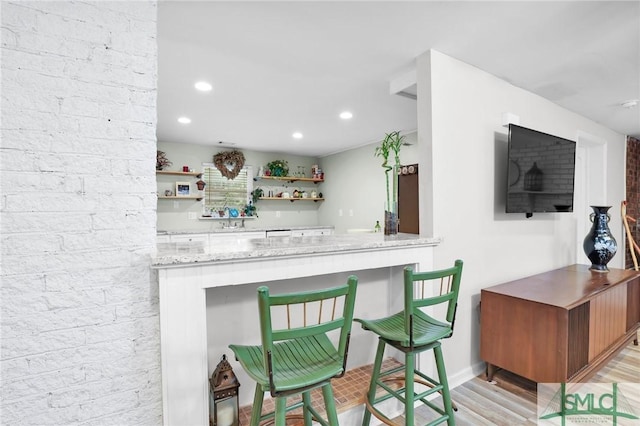 bar featuring light stone countertops and light hardwood / wood-style flooring