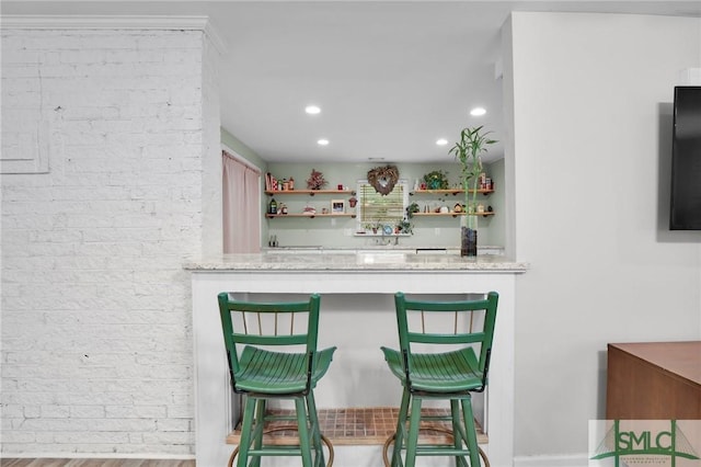 bar with light stone counters and light hardwood / wood-style flooring