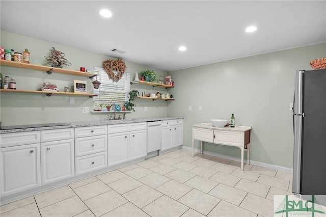 kitchen featuring light stone countertops, black electric stovetop, white cabinets, sink, and stainless steel fridge