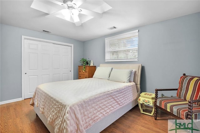 bedroom with a skylight, wood-type flooring, a closet, and ceiling fan