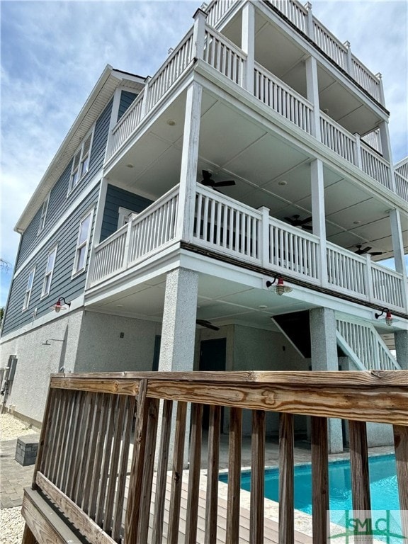 view of side of property featuring an outdoor pool and a balcony