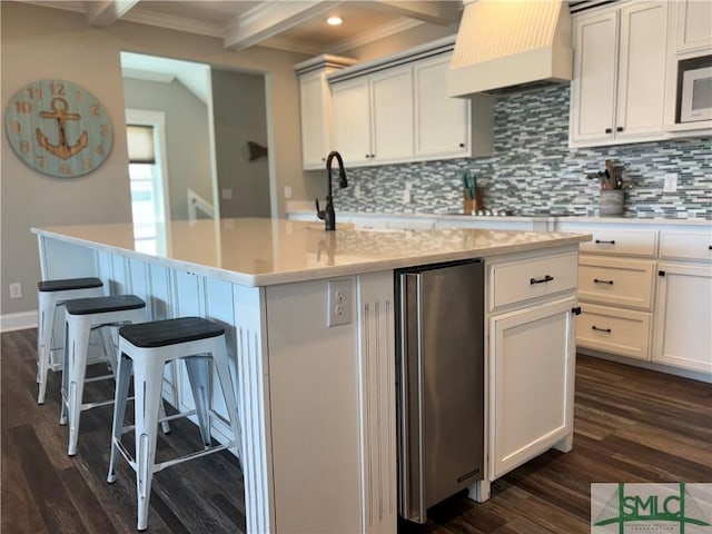 kitchen with dark wood finished floors, backsplash, crown molding, and freestanding refrigerator