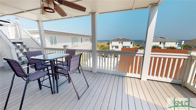 wooden deck with stairway, ceiling fan, outdoor dining space, and a residential view