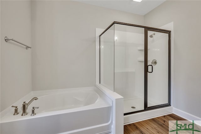 bathroom featuring wood-type flooring and shower with separate bathtub