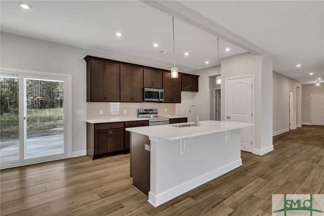 kitchen with a center island with sink, light hardwood / wood-style floors, sink, and stainless steel appliances