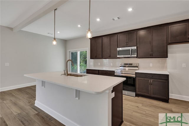 kitchen featuring pendant lighting, sink, stainless steel appliances, and light hardwood / wood-style floors