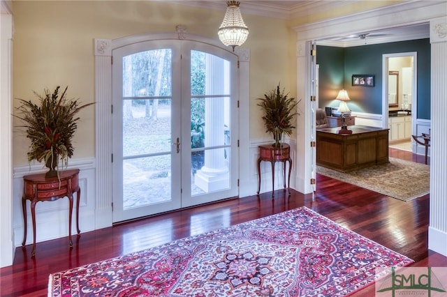 doorway to outside featuring a wainscoted wall, ornamental molding, wood finished floors, french doors, and a decorative wall