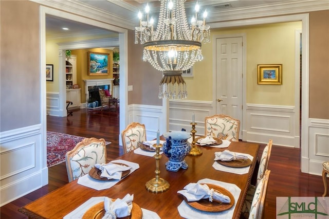 dining space with visible vents, wood finished floors, an inviting chandelier, crown molding, and a high end fireplace