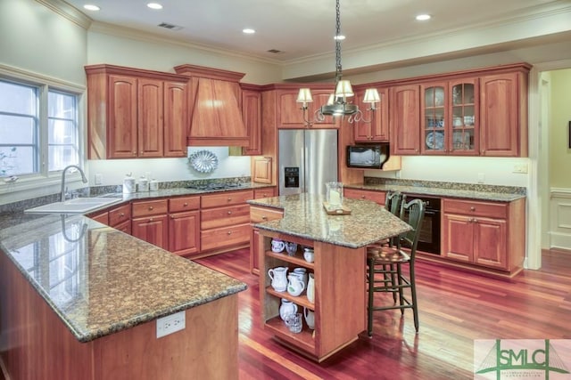 kitchen featuring visible vents, appliances with stainless steel finishes, a kitchen breakfast bar, premium range hood, and a sink