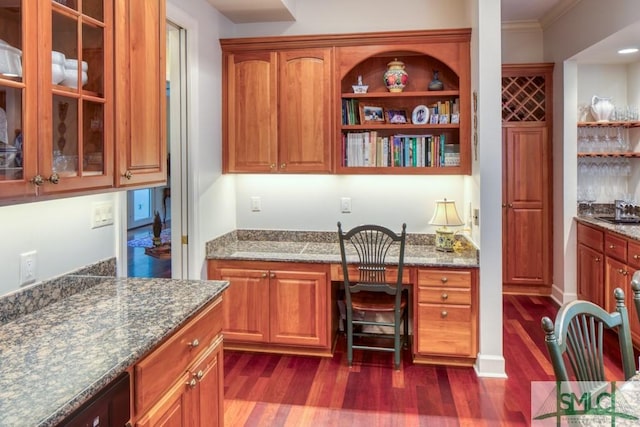 interior space with baseboards, dark wood-type flooring, crown molding, built in desk, and a sink