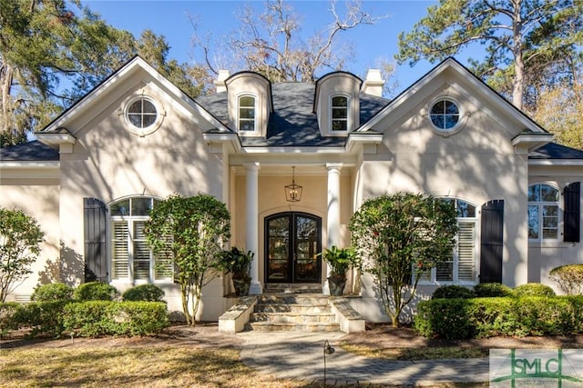 view of front of property with french doors, a chimney, and stucco siding