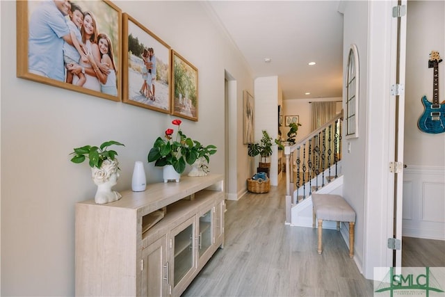 hallway with ornamental molding and light hardwood / wood-style floors