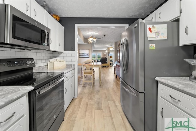 kitchen with tasteful backsplash, a textured ceiling, light wood-type flooring, stainless steel appliances, and white cabinets