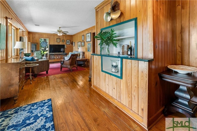 kitchen featuring ceiling fan, wooden walls, hardwood / wood-style floors, and a textured ceiling