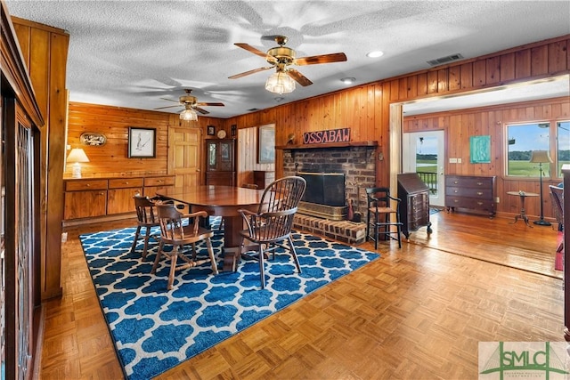 dining space with light parquet flooring, a textured ceiling, and wood walls