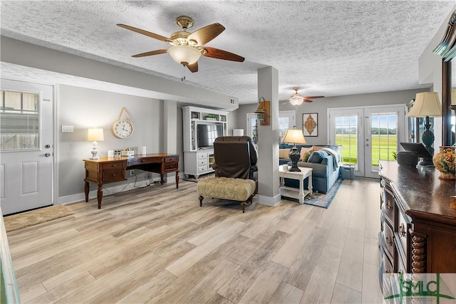 sitting room with ceiling fan, light hardwood / wood-style flooring, french doors, and a textured ceiling