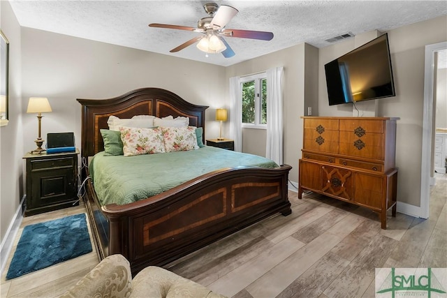 bedroom with ceiling fan, light hardwood / wood-style flooring, and a textured ceiling