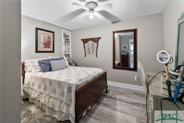 bedroom featuring ceiling fan, hardwood / wood-style flooring, and a textured ceiling