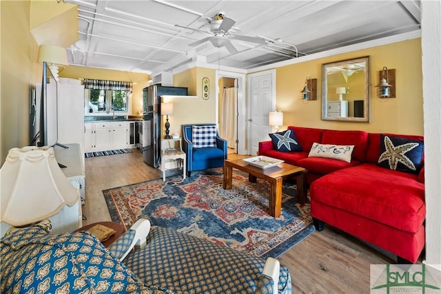 living room featuring ceiling fan, wood-type flooring, and sink