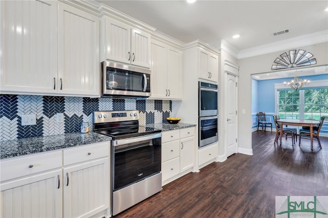 kitchen with a notable chandelier, crown molding, tasteful backsplash, dark wood-type flooring, and appliances with stainless steel finishes