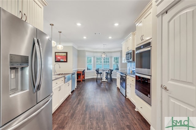 kitchen featuring stainless steel appliances, sink, crown molding, light stone countertops, and dark wood-type flooring