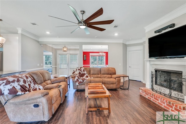 living room featuring ceiling fan, crown molding, dark hardwood / wood-style flooring, and a brick fireplace