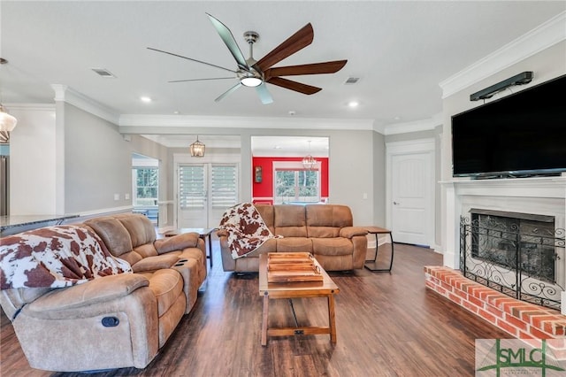 living room with crown molding, a brick fireplace, dark hardwood / wood-style floors, and ceiling fan