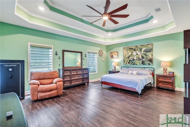 bedroom featuring ceiling fan, a tray ceiling, dark hardwood / wood-style flooring, and crown molding