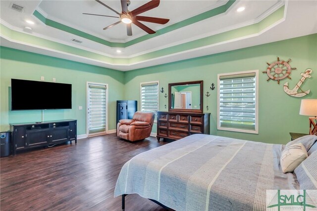 bedroom with multiple windows, dark hardwood / wood-style floors, and a raised ceiling