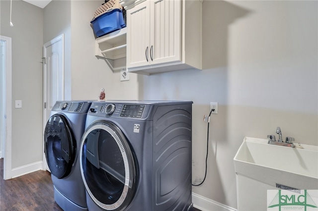 laundry area with washing machine and clothes dryer, dark hardwood / wood-style flooring, sink, and cabinets