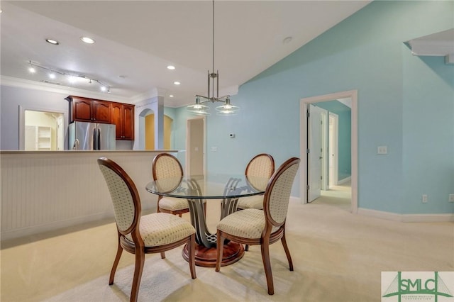 dining area featuring a notable chandelier, vaulted ceiling, light colored carpet, and crown molding