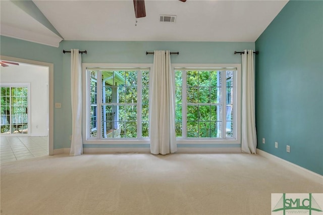 carpeted empty room featuring ceiling fan, a wealth of natural light, and vaulted ceiling