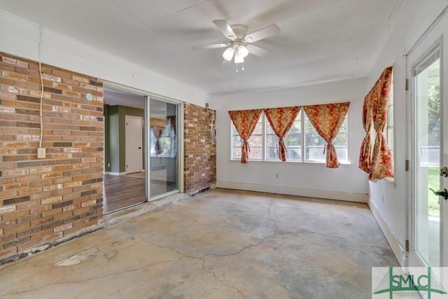 empty room with concrete floors, ceiling fan, and brick wall