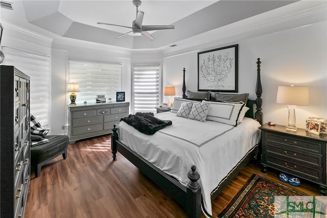 bedroom with a raised ceiling, ornamental molding, ceiling fan, and dark hardwood / wood-style flooring