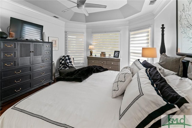 bedroom with ceiling fan, ornamental molding, dark hardwood / wood-style flooring, and a raised ceiling