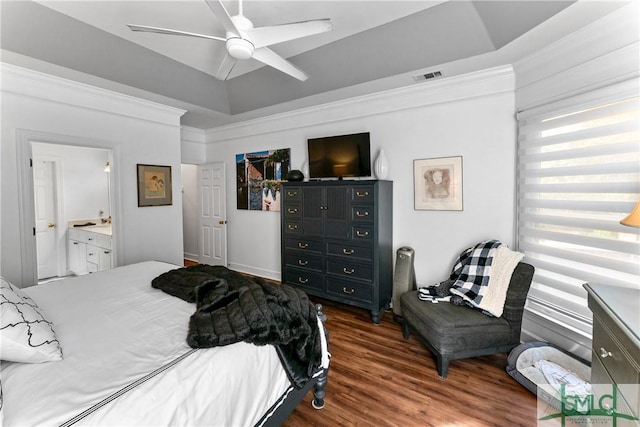 bedroom featuring ornamental molding, dark wood-type flooring, ensuite bathroom, and a tray ceiling