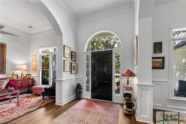 entrance foyer with dark hardwood / wood-style flooring, crown molding, a healthy amount of sunlight, and a high ceiling