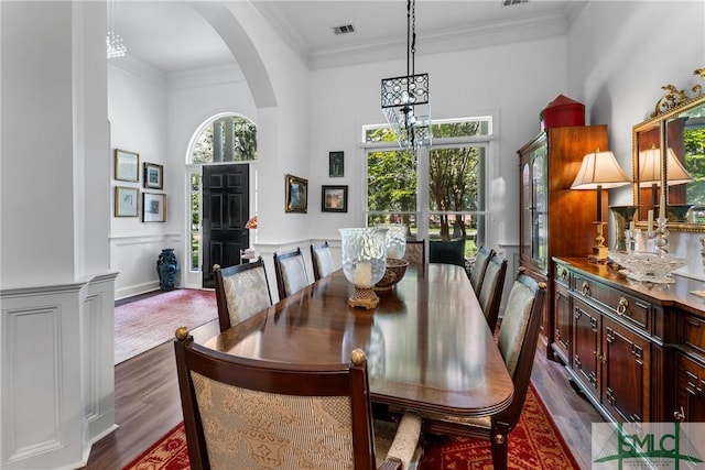 dining space with a high ceiling, crown molding, dark wood-type flooring, and a wealth of natural light