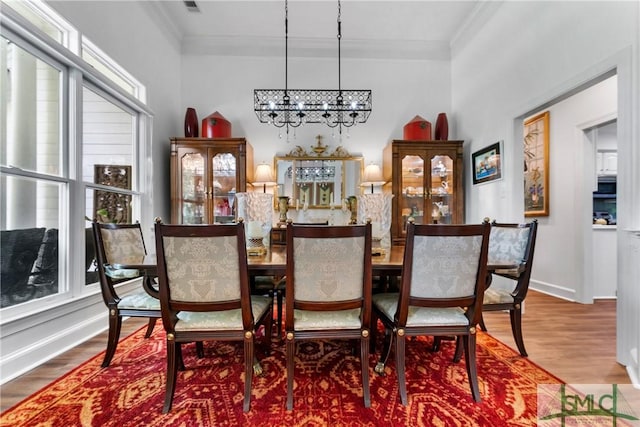 dining area with a notable chandelier, hardwood / wood-style flooring, and ornamental molding